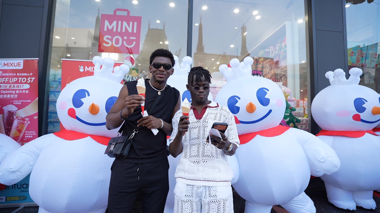 Happy customers with MIXUE soft serve cones and giant snowman mascots at store opening